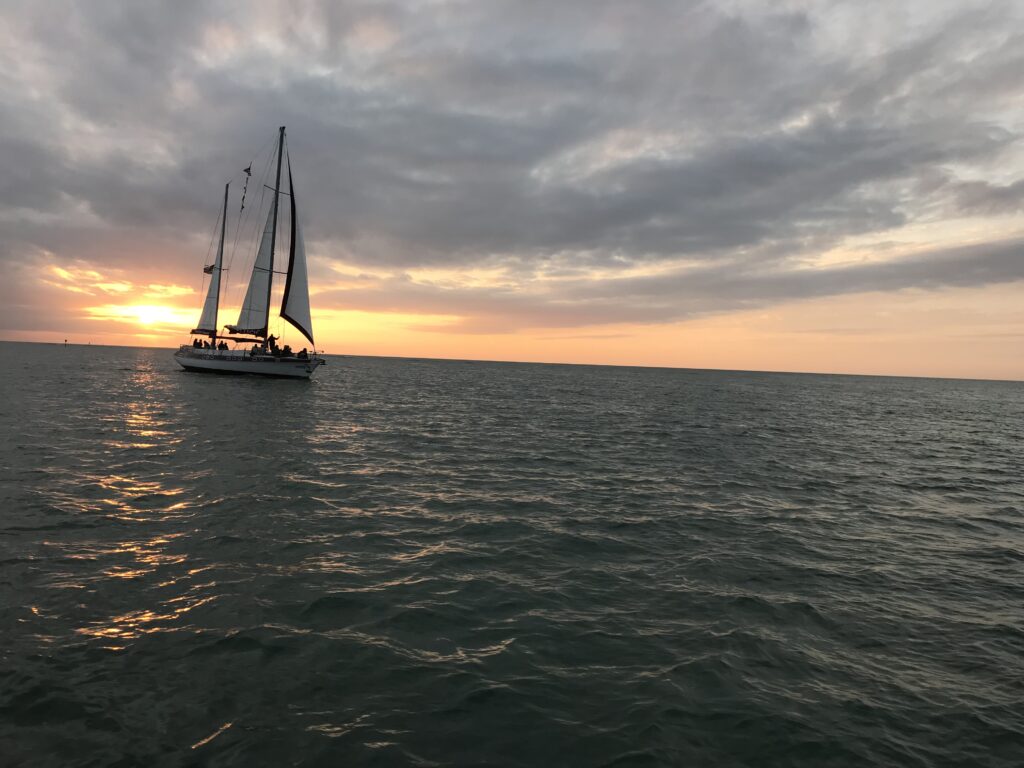 A sailboat sails in Tampa Bay at sunset.
