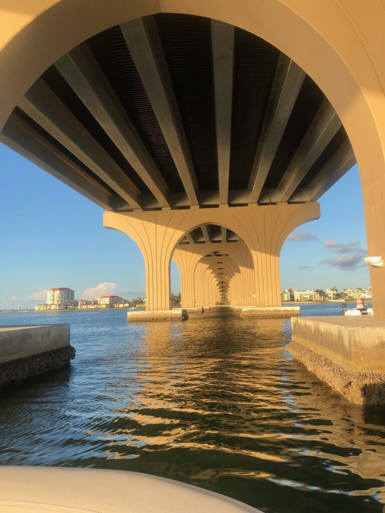 A boat under a bridge in the water.