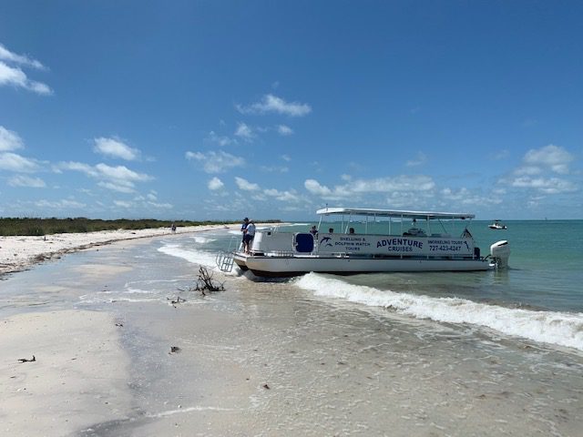A boat docked on a sandy beach near a body of water.