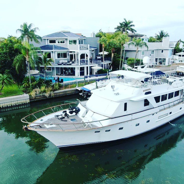 Luxury yacht rentals moored in a residential canal with waterfront homes in the background in Clearwater.