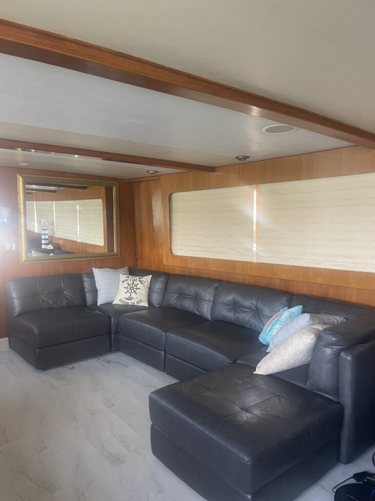 Interior of a yacht cabin featuring a leather sectional sofa and wood paneling, available for charters in Tampa, Clearwater, St. Petersburg.