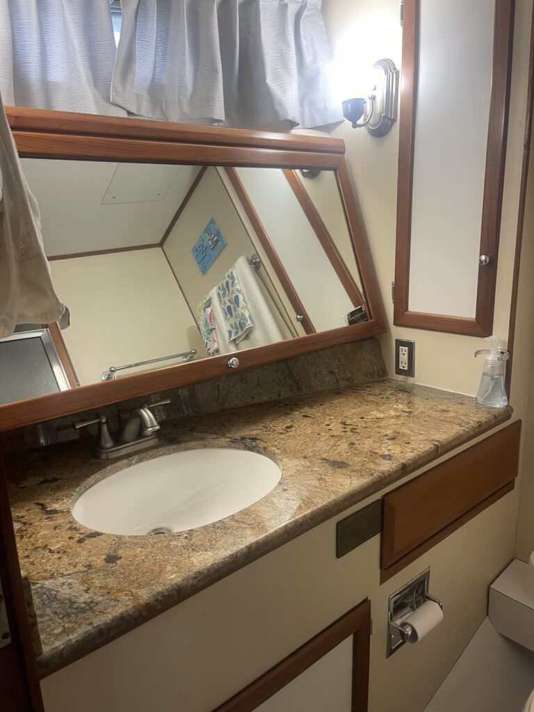 A yacht bathroom vanity with granite countertop, undermount sink, and wood cabinetry.