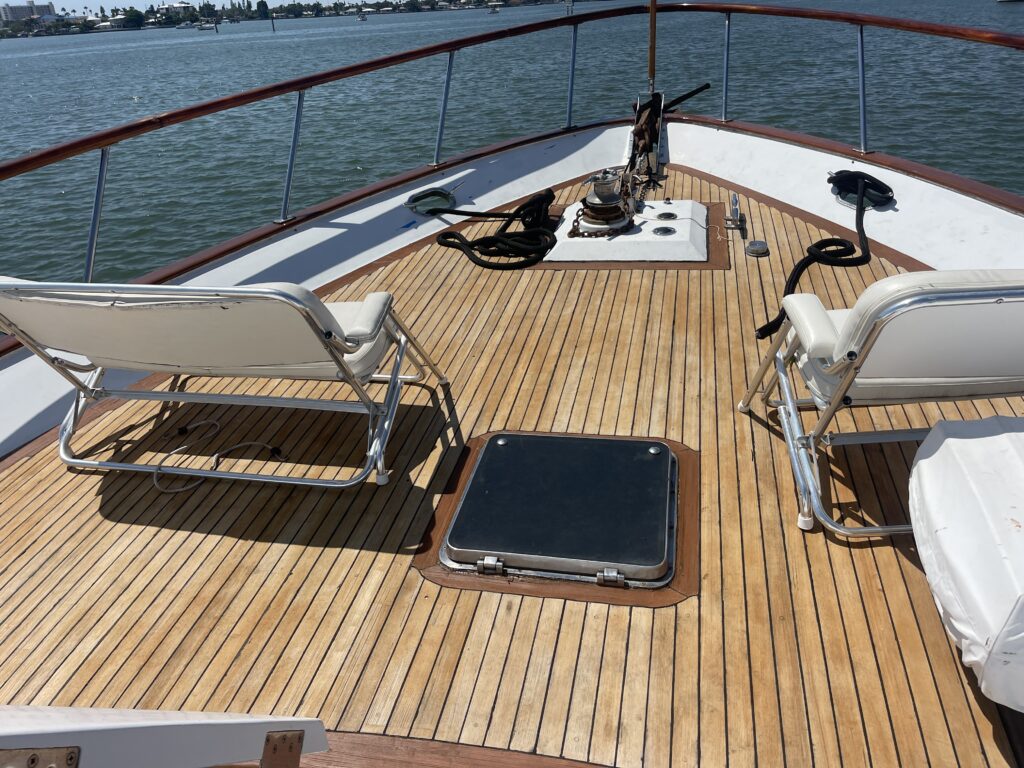 Deck of a boat with lounging chairs and nautical equipment.